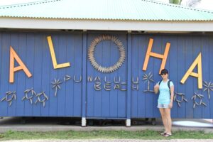Glynis standing in front of Aloha sign